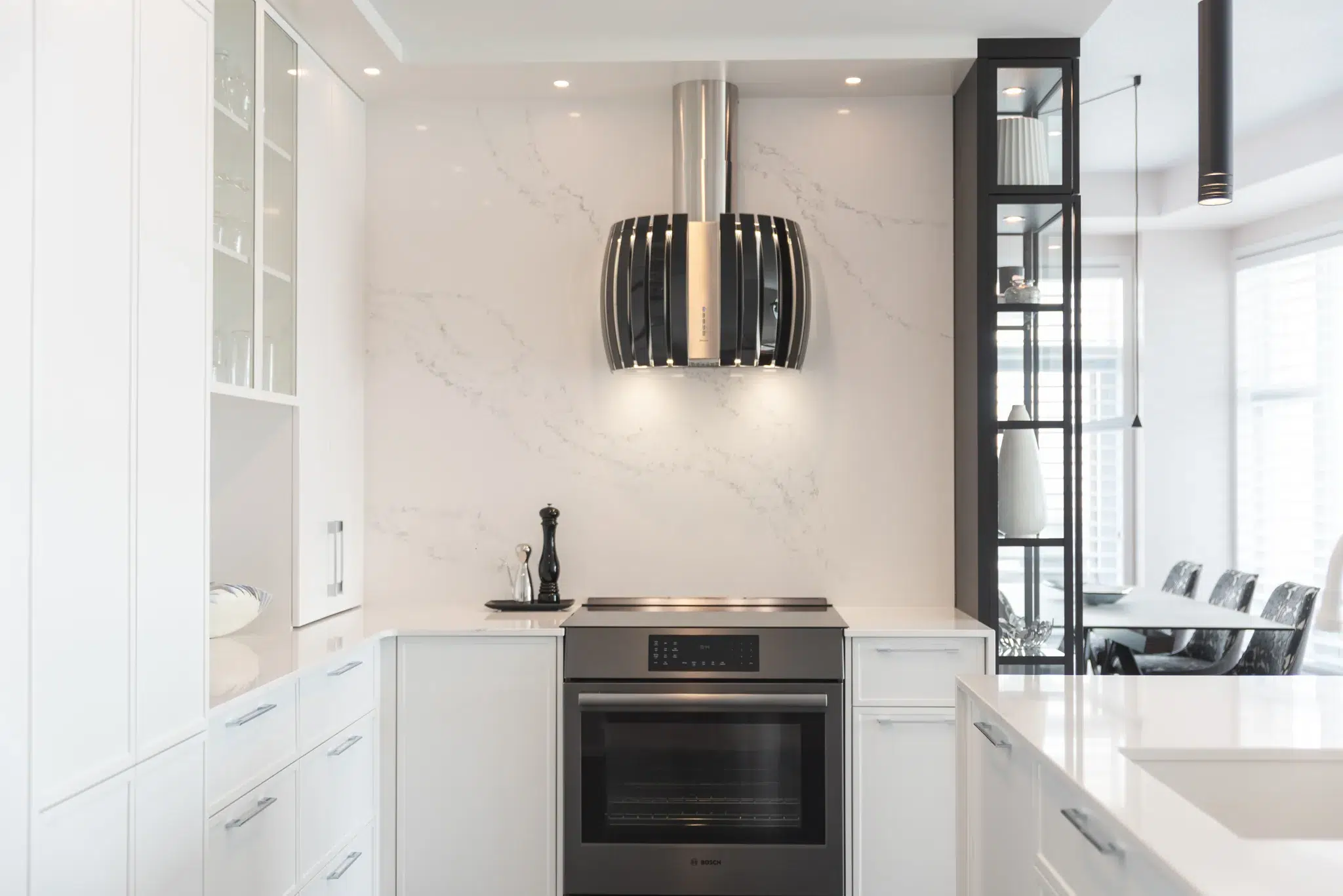 Cuisine blanche avec plan de travail en marbre et hotte design suspendue.