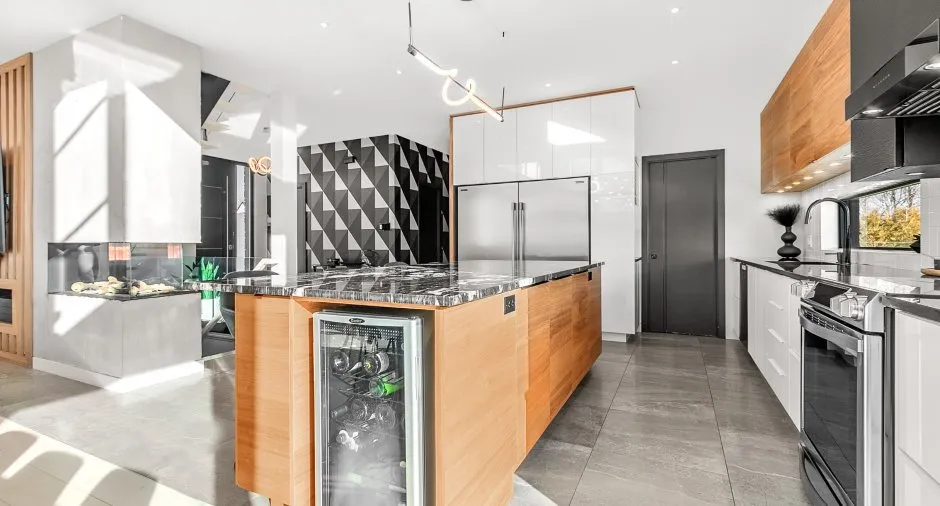 Cuisine luxueuse avec îlot central en bois et marbre, électroménagers haut de gamme et cheminée design.