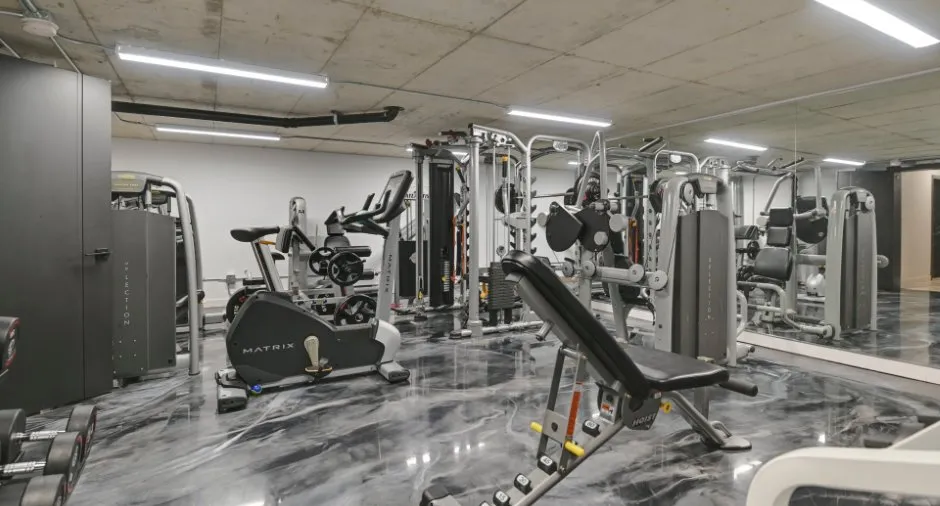 Salle de gym haut de gamme avec équipements professionnels, sol en résine et murs en béton brut.