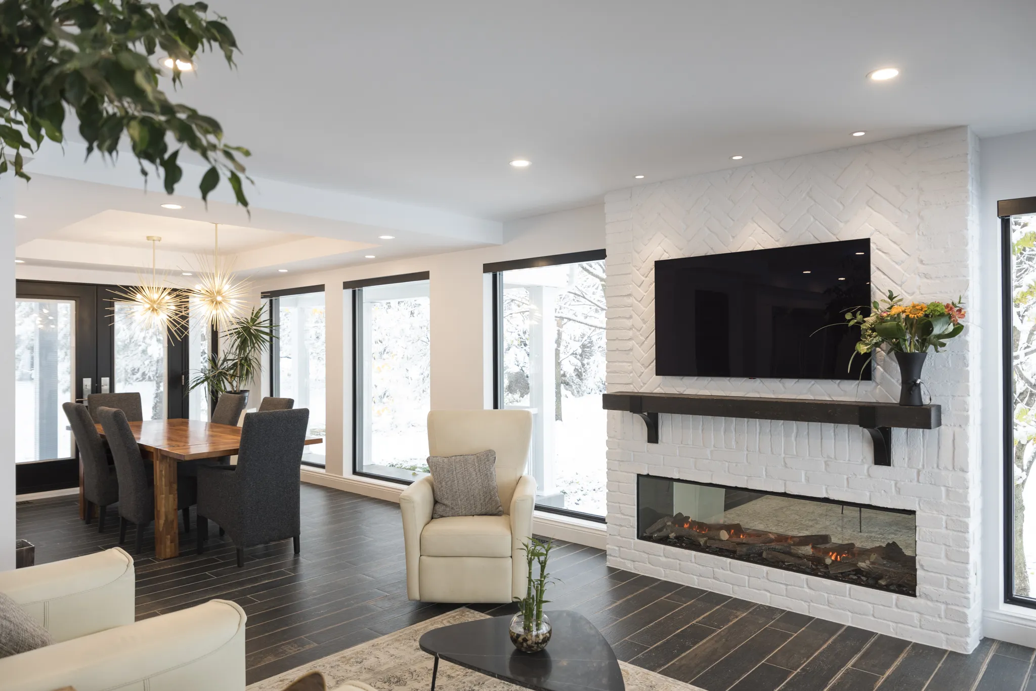 Salon contemporain avec cheminée blanche en brique, télé murale et ambiance chaleureuse.